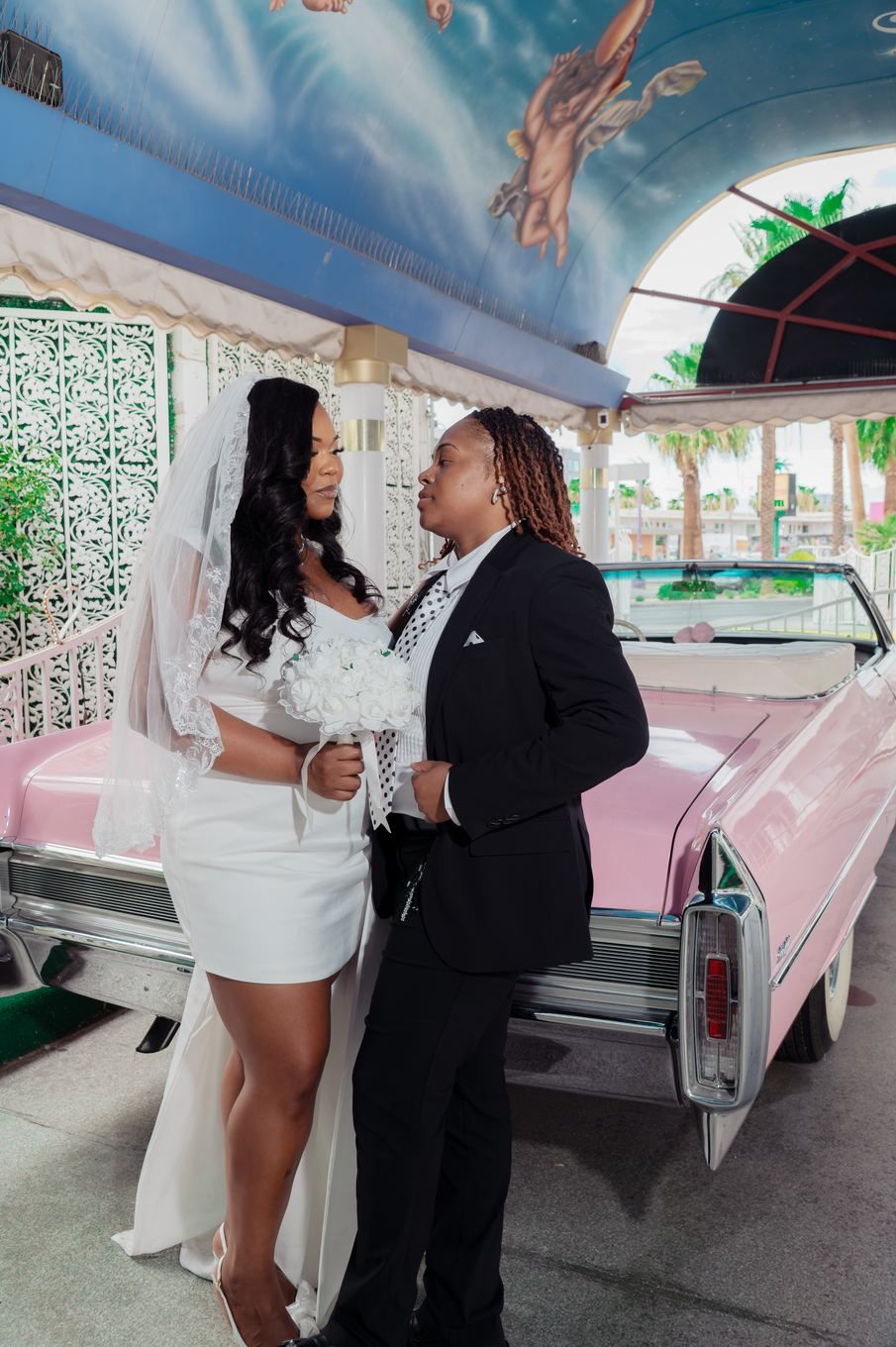 Couple sharing a moment by the pink Cadillac