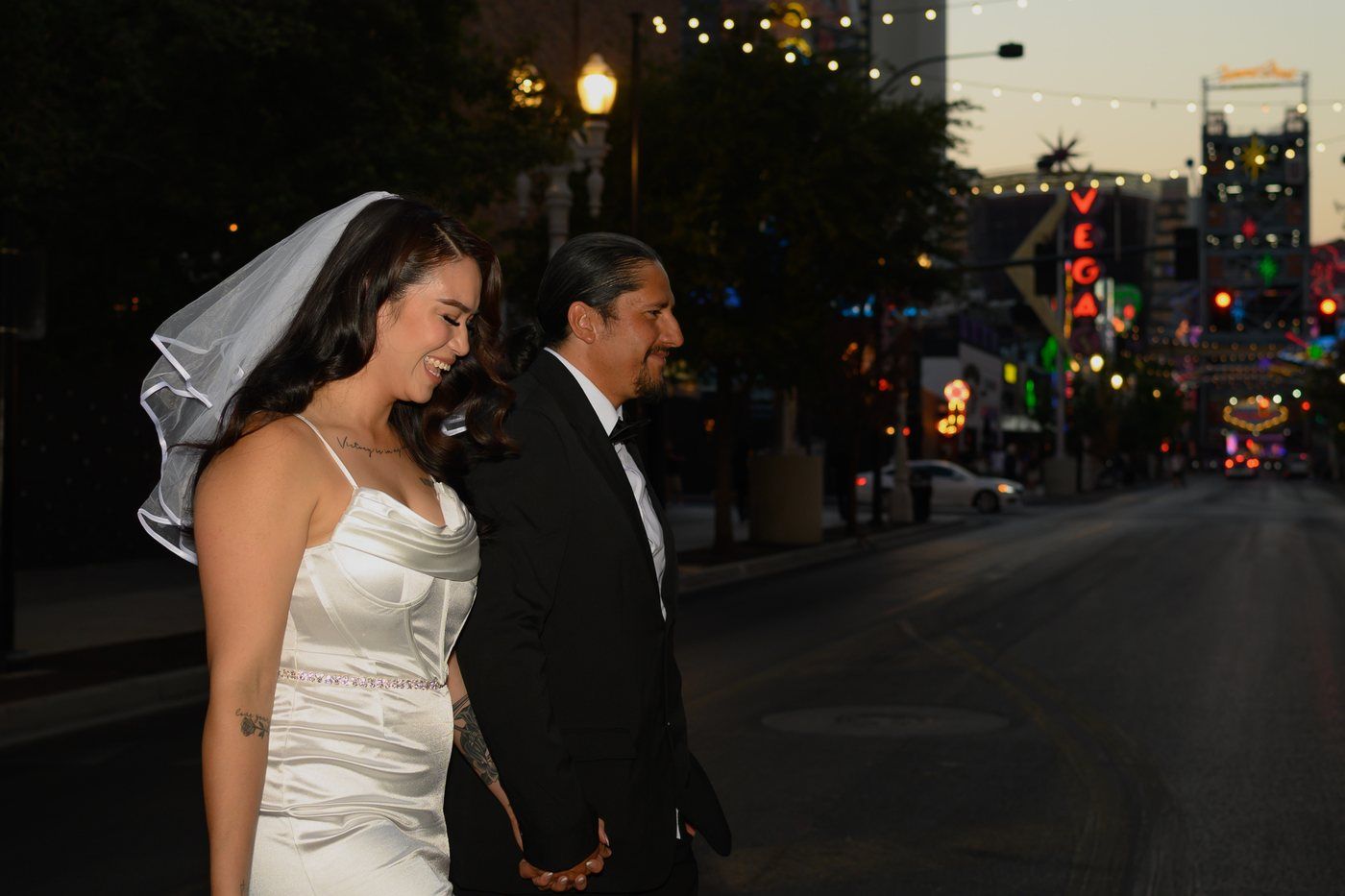 Newlyweds walking hand in hand along Fremont Street at dusk