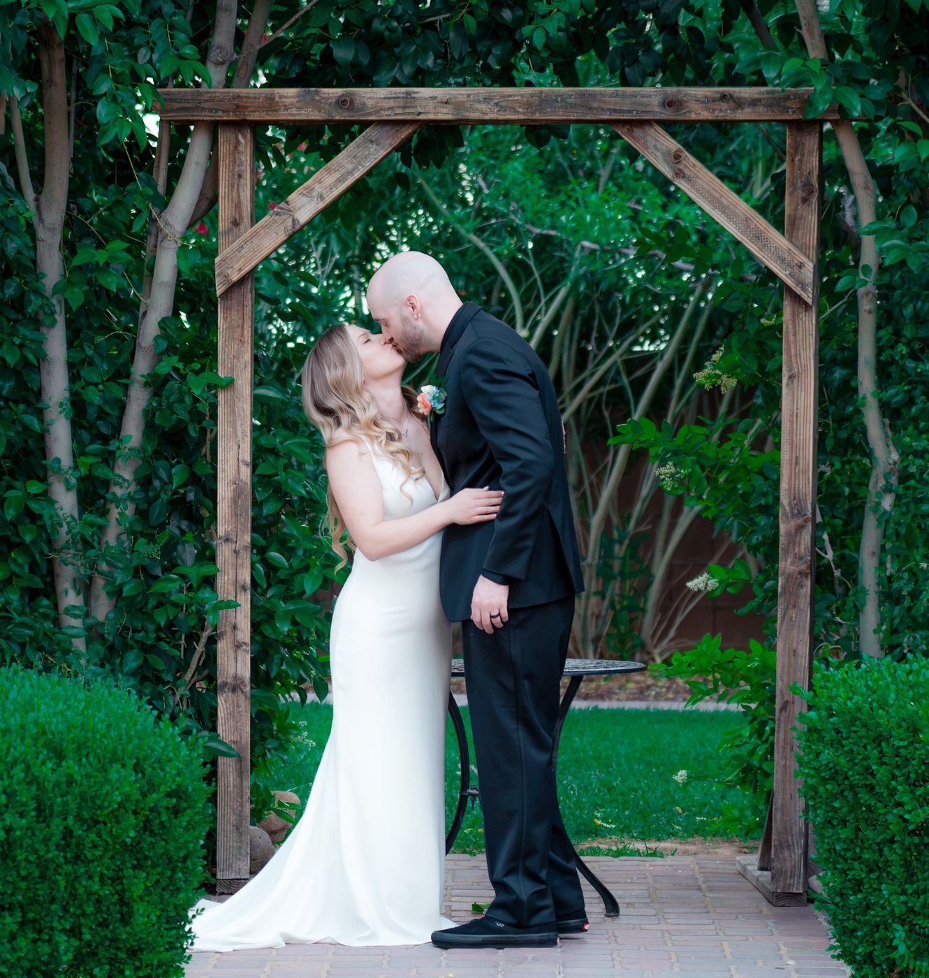 First kiss beneath a wooden garden arch