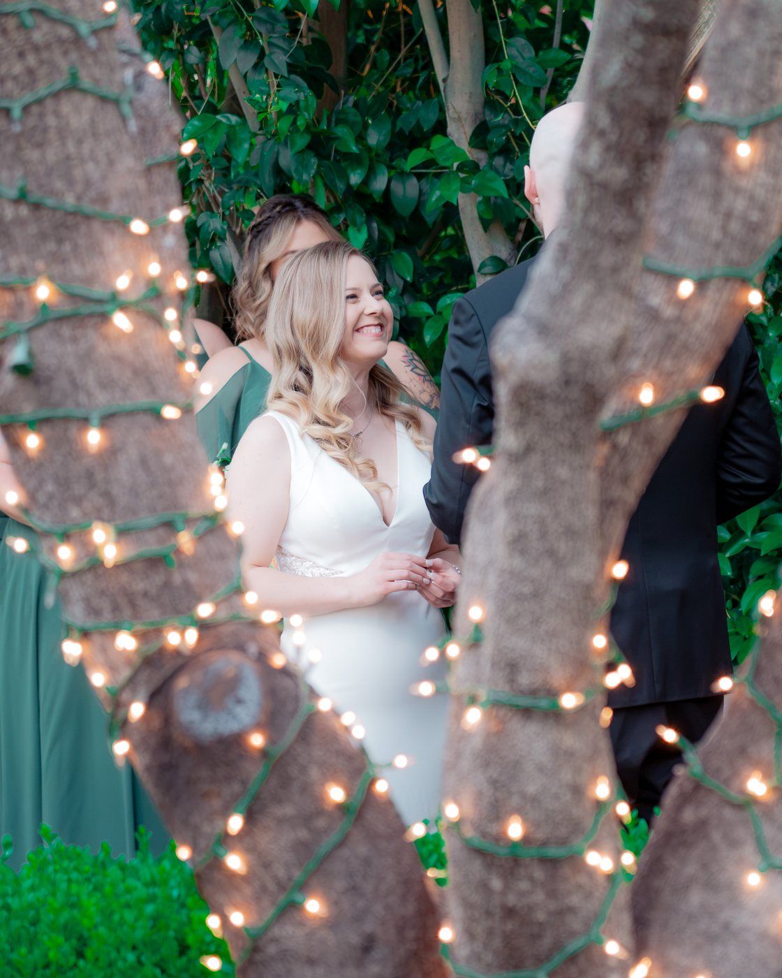 Bride during the ceremony framed by string lights