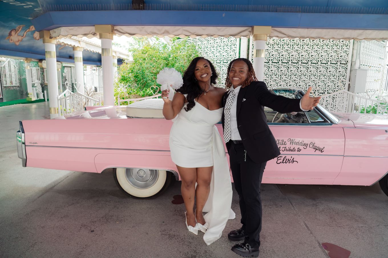 Newlyweds celebrating by the pink Cadillac at a Las Vegas chapel