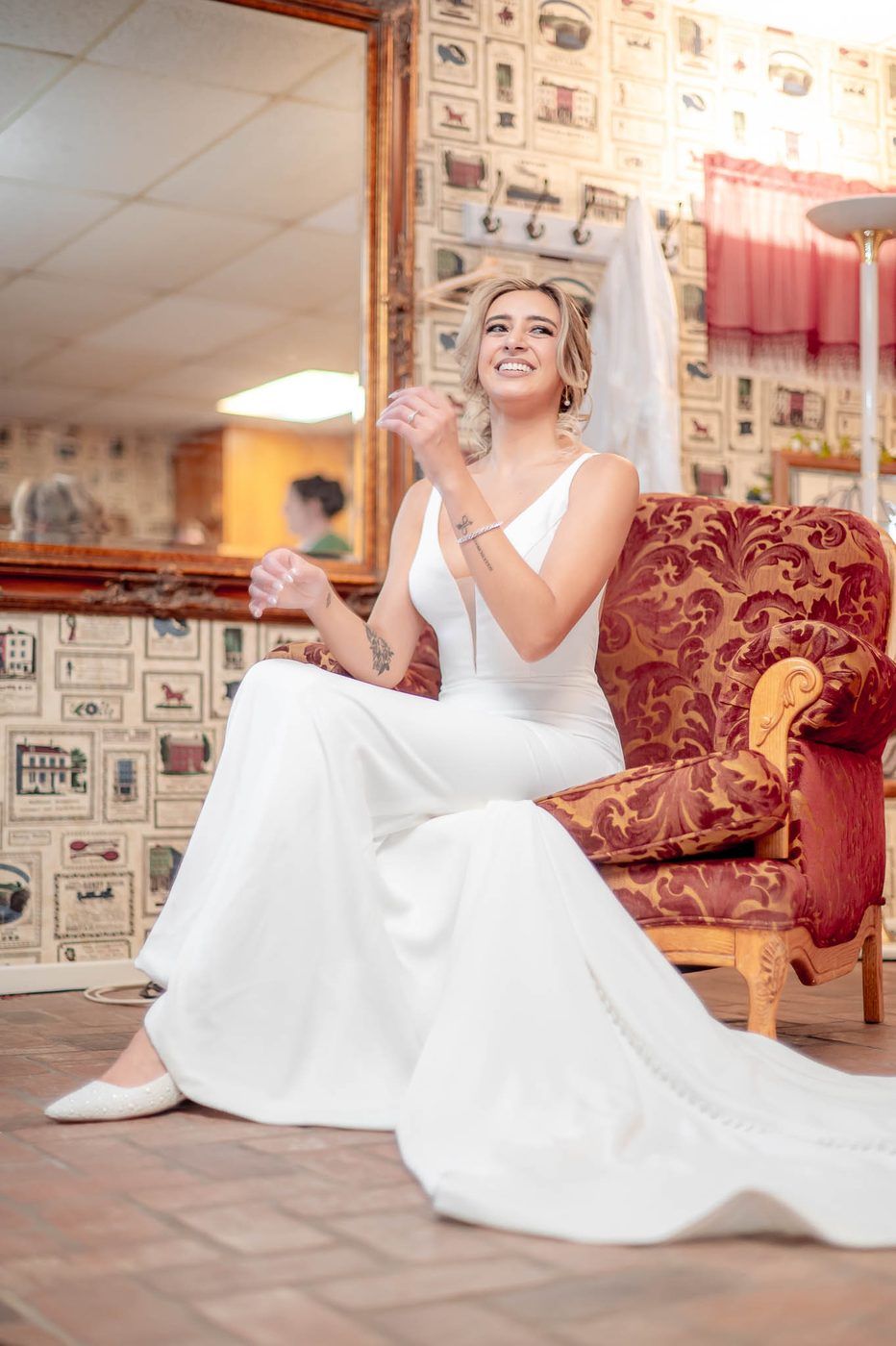 Bride laughing in a vintage armchair during getting ready
