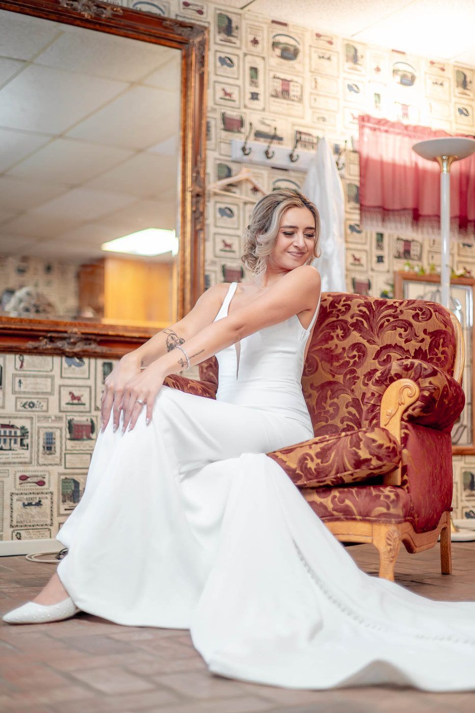 Bride in her gown seated in a vintage armchair