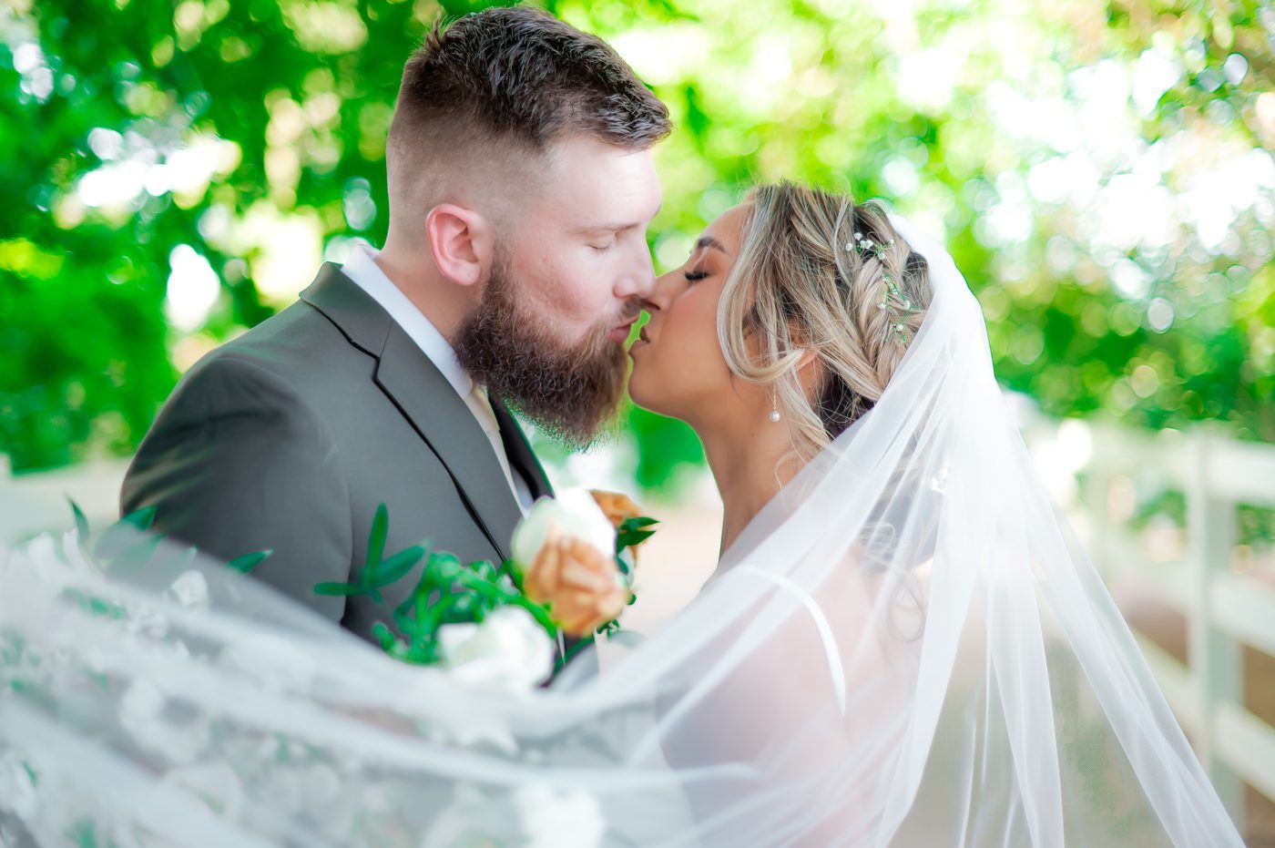 Bride and groom kiss beneath a flowing veil